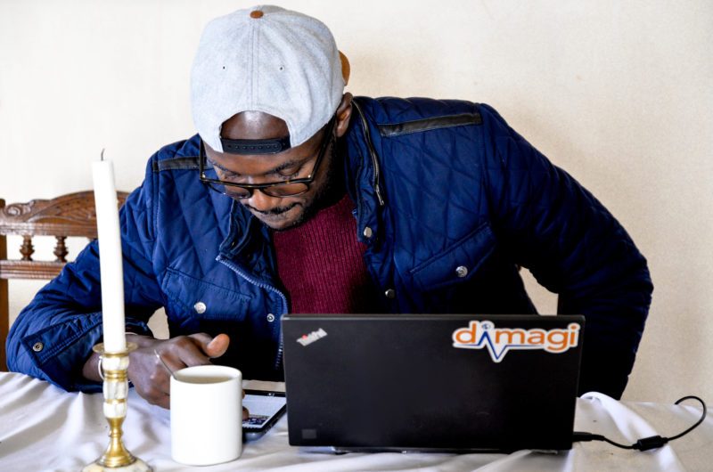 A man working on a Dimagi-branded laptop with a mug of coffee