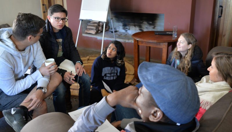 Dimagi team members talking in a small group beside a fireplace at a retreat