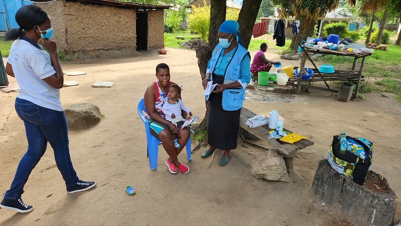 Frontline workers conducting a community home visit for a social impact program case management initiative, demonstrating the need for mobile accessibility and client progress tracking in the field.