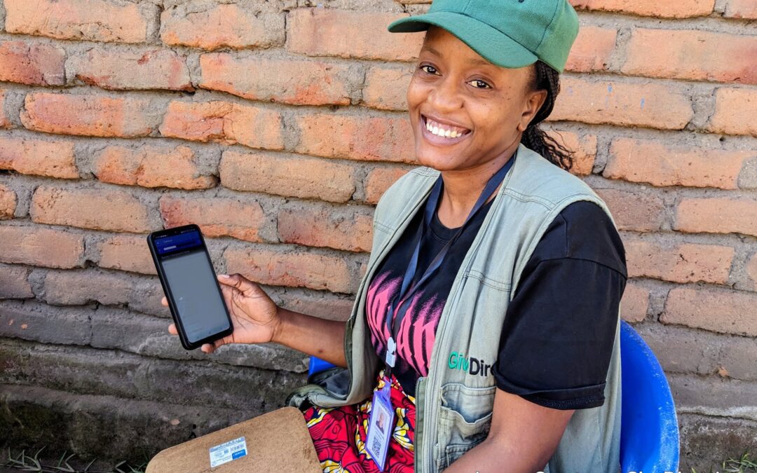 A GiveDirectly field officer using CommCare on a smartphone, a scalable TaroWorks alternative for cash transfer programs in remote areas.